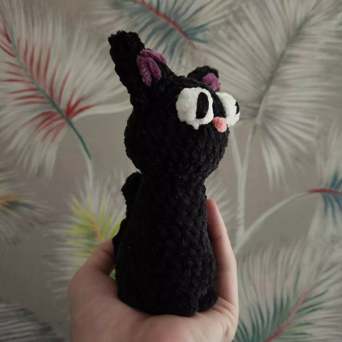 Chat Jiji en crochet - vue latérale sur le nœud rouge